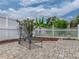 A brick-paved patio in backyard with a metal chair and a white picket fence with tasteful landscaping behind at 27231 Liriope Ct, Wesley Chapel, FL 33544