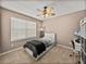 Neutral bedroom with a ceiling fan, large window with blinds, and a cozy bed setup at 27231 Liriope Ct, Wesley Chapel, FL 33544