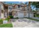 Tan townhome featuring a well-manicured lawn, mature landscaping, and attached one-car garage at 3073 Overlook Pl, Clearwater, FL 33760