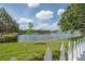 Picturesque view of the lake from the grass, framed by a classic white picket fence at 3073 Overlook Pl, Clearwater, FL 33760