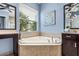 Bathroom featuring a soaking tub with neutral tile surround, dual vanity, and a decorative butterfly painting at 31050 Spruceberry Ct, Wesley Chapel, FL 33543