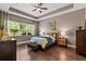 Inviting bedroom featuring tray ceilings, hardwood floors, and a large window with a view at 31050 Spruceberry Ct, Wesley Chapel, FL 33543