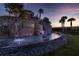 Community entrance featuring a waterfall and stone architecture at dusk at 31050 Spruceberry Ct, Wesley Chapel, FL 33543