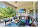 Covered patio with outdoor furniture, a wall-mounted TV, and views of the lush greenery, perfect for outdoor entertaining at 31050 Spruceberry Ct, Wesley Chapel, FL 33543