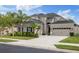 Charming two-story home showcasing a three-car garage and attractive landscaping with palm trees and shrubbery at 3142 Stonegate Falls Dr, Land O Lakes, FL 34638
