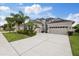 Beautiful two-story home featuring a three-car garage, well-manicured lawn, and lush tropical landscaping at 3142 Stonegate Falls Dr, Land O Lakes, FL 34638