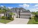 Beautiful two-story home featuring a three-car garage, well-manicured lawn, and lush tropical landscaping at 3142 Stonegate Falls Dr, Land O Lakes, FL 34638