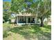 Charming home exterior with a cozy front porch, lush lawn, and mature shade tree at 425 E Orange St, Tarpon Springs, FL 34689
