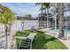 Relaxing backyard lounge area with artificial turf, lounge chairs, and a screened-in pool at 4847 Harbor Woods Dr, Palm Harbor, FL 34683