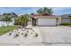 Well-maintained home featuring a two-car garage and beautiful landscaping including flowers and palm trees at 4847 Harbor Woods Dr, Palm Harbor, FL 34683
