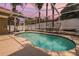 Beautiful kidney-shaped pool enclosed in a screened lanai with a white fence backdrop at 4847 Harbor Woods Dr, Palm Harbor, FL 34683