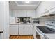 Bright kitchen featuring white cabinets, appliances, wood floors and a view to another room at 4917 Puritan Cir # 105, Tampa, FL 33617