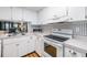 Bright kitchen featuring white cabinets, appliances, wood floors and a view to another room at 4917 Puritan Cir # 105, Tampa, FL 33617
