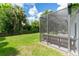 Green backyard featuring a screened-in lanai with a wood bench perfect for outdoor relaxation and enjoyment at 6116 Skylarkcrest Dr, Lithia, FL 33547