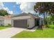 Single-story house with well-maintained lawn, gray garage door and trim, and mature tree providing shade at 6116 Skylarkcrest Dr, Lithia, FL 33547