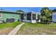View of backyard with a green house, screened porch, and a stone pathway on a grassy lawn at 6904 11Th Ave E, Palmetto, FL 34221