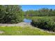 View of a waterway, surrounded by grass, plants, and trees, bordering an area of rocky shoreline at 6904 11Th Ave E, Palmetto, FL 34221