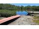 Tranquil setting with a canoe on the bank next to the water's edge, a pier, and lush foliage at 6904 11Th Ave E, Palmetto, FL 34221