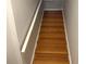 A well lit staircase with hardwood floors and a white handrail leads upwards between gray painted walls at 716 Seagate Dr # 716, Tampa, FL 33602