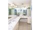 Bright bathroom with dual sinks, marble countertops, decorative lighting and tile flooring at 7812 Turnbridge Dr, Port Richey, FL 34668