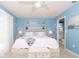 Bright blue bedroom features tile floors, queen bed, ceiling fan, and access to the bathroom at 7812 Turnbridge Dr, Port Richey, FL 34668