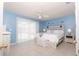 Bright bedroom with light blue walls, tile flooring, ceiling fan, and slider to the pool area at 7812 Turnbridge Dr, Port Richey, FL 34668