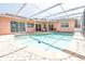 Inviting screened-in pool area with a charming mural and brick-paved deck for outdoor enjoyment at 7812 Turnbridge Dr, Port Richey, FL 34668