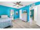 Vibrant bedroom with blue walls, wood floors, ceiling fan, and adjacent doorway to an additional room at 8130 129Th N Ln, Seminole, FL 33776
