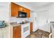 Kitchen with wooden cabinets, white appliances, and tile flooring, adjacent to the living space at 8130 129Th N Ln, Seminole, FL 33776