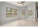 Well-lit living room with large windows and tile flooring beneath a ceiling fan at 8408 Nuzum Rd, Brooksville, FL 34613
