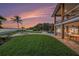 A tropical backyard has a large well-manicured lawn, pool, fire pit, and covered porch under a lovely sunset at 8488 35Th N Ave, St Petersburg, FL 33710