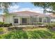 Backyard view of home and screened patios, showing well-maintained lawn and tidy landscaping at 10260 Devonshire Lake Dr, Tampa, FL 33647