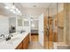 Clean bathroom featuring double sinks, wood cabinets, glass shower, and a view of the bedroom at 10260 Devonshire Lake Dr, Tampa, FL 33647