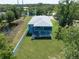 Aerial view showcases a two-story blue house with ponds, green lawns, and beautiful surrounding trees at 1033 Hammock Cir, Tarpon Springs, FL 34688