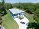 Aerial view of a blue two-story house boasting a lengthy driveway, a spacious front yard, and lush greenery at 1033 Hammock Cir, Tarpon Springs, FL 34688