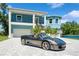 Two-story blue home with manicured landscaping, a white driveway, and a gray luxury car at 1033 Hammock Cir, Tarpon Springs, FL 34688