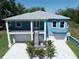Stunning two-story blue home featuring double garages, a spacious balcony, and a beautifully paved driveway at 1033 Hammock Cir, Tarpon Springs, FL 34688
