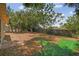 Spacious backyard featuring mature trees, partial fencing, and a mix of natural and synthetic ground cover at 10817 Kingsbridge Rd, Port Richey, FL 34668