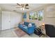 Well-lit living room with a blue sofa, closet and a work area with a view of the yard at 10817 Kingsbridge Rd, Port Richey, FL 34668
