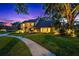 Charming two-story home with a well-manicured lawn, walkway, and lush landscaping illuminated at dusk at 11804 Carrollwood Village Cv, Tampa, FL 33618