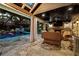An outdoor living space features a fireplace, seating, a tv and views of the pool at 11804 Carrollwood Village Cv, Tampa, FL 33618