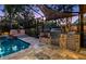 Outdoor kitchen and in-ground pool area with travertine tile and stainless steel appliances at 11804 Carrollwood Village Cv, Tampa, FL 33618