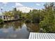 Dock on a waterway with lush vegetation and a house in the background on a sunny day at 119 18Th Nw St, Ruskin, FL 33570
