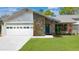 Charming home with a stone accent wall, well-maintained lawn, and a modern garage door at 13891 Feather Sound Dr, Clearwater, FL 33762
