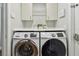 Laundry area showcasing front-load Samsung washer and dryer under storage cabinets at 14078 Leeward Dr, Seminole, FL 33776