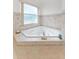 Bright bathroom featuring a corner soaking tub with tile surround and a window allowing natural light at 15703 Walden Ave, Tampa, FL 33618