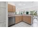 Kitchen area with stainless steel dishwasher, light wood cabinets and open to living space at 15703 Walden Ave, Tampa, FL 33618
