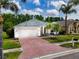 Charming single-story home with a two-car garage, red brick driveway, mature landscaping and lawn at 16113 Rambling Rd, Odessa, FL 33556