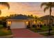 Charming single-story home with a two-car garage, red brick driveway and manicured lawn at sunset at 16113 Rambling Rd, Odessa, FL 33556