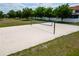 Outdoor sand volleyball court surrounded by lush greenery and a white fence offers recreational opportunities at 16113 Rambling Rd, Odessa, FL 33556